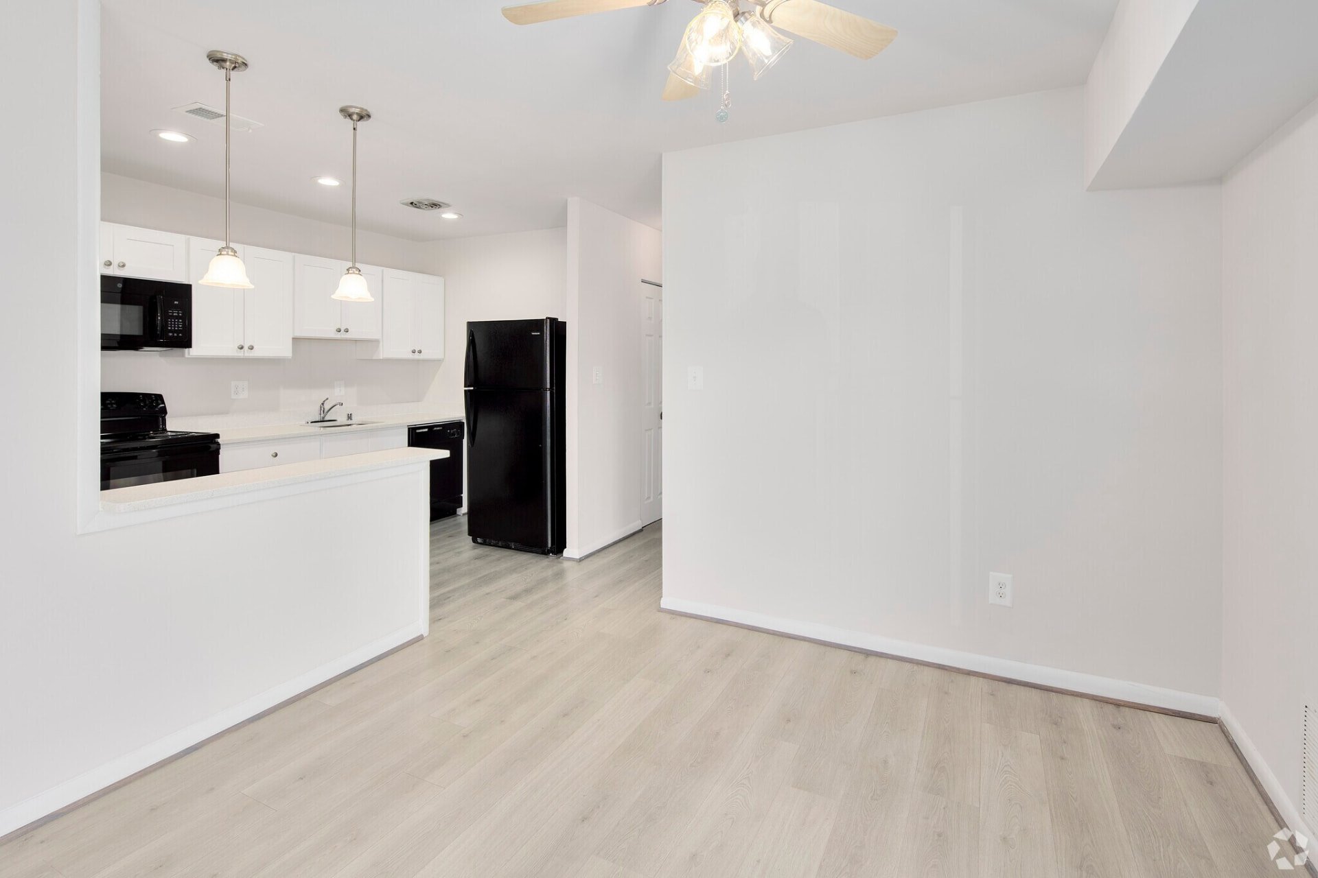 Living and dining area with white kitchen cabinets and black appliances