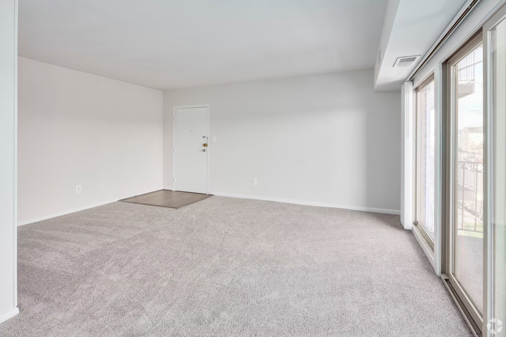 One-bedroom carpeted living room beside the balcony doors