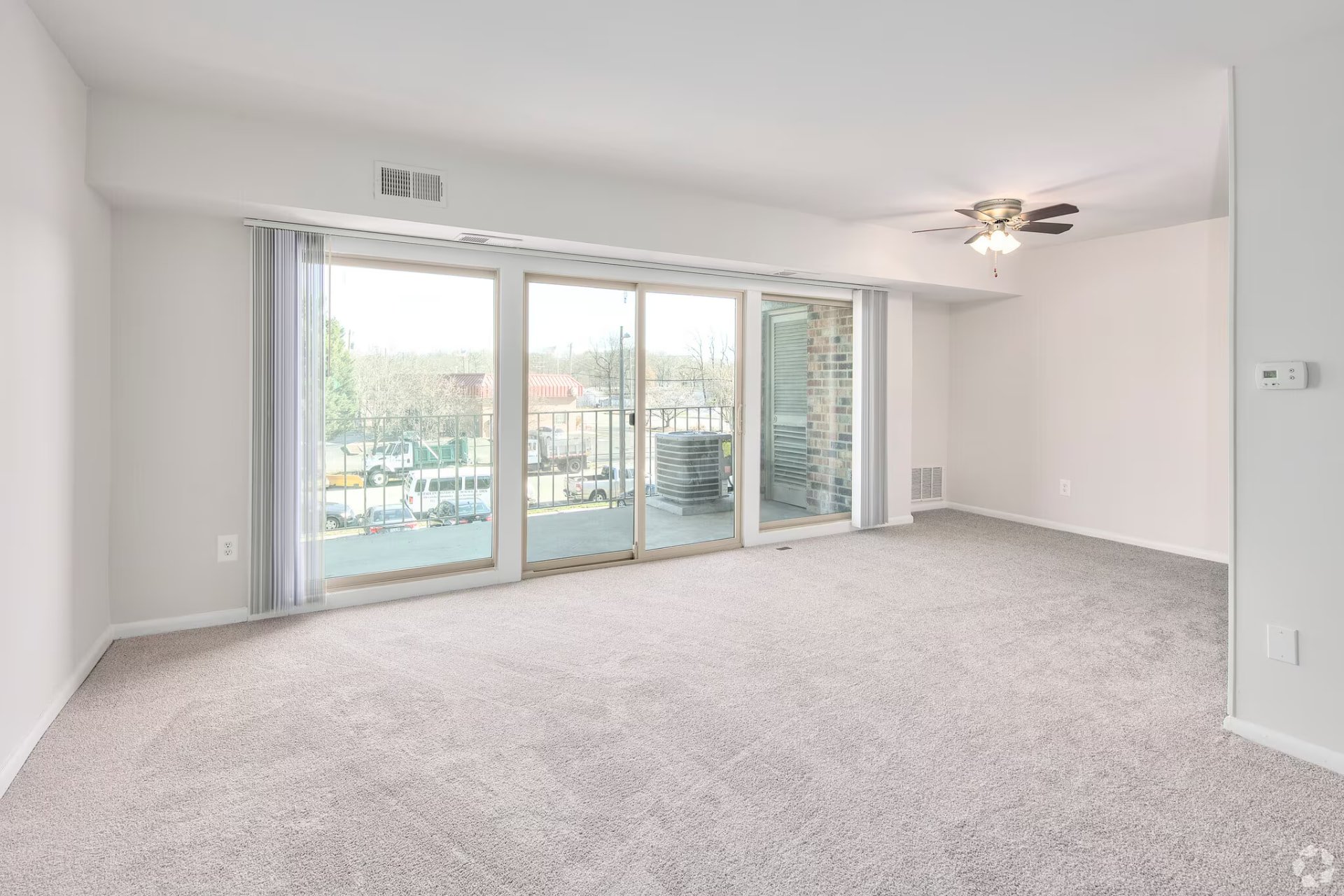 One-bedroom living room with wide balcony doors and ceiling fan