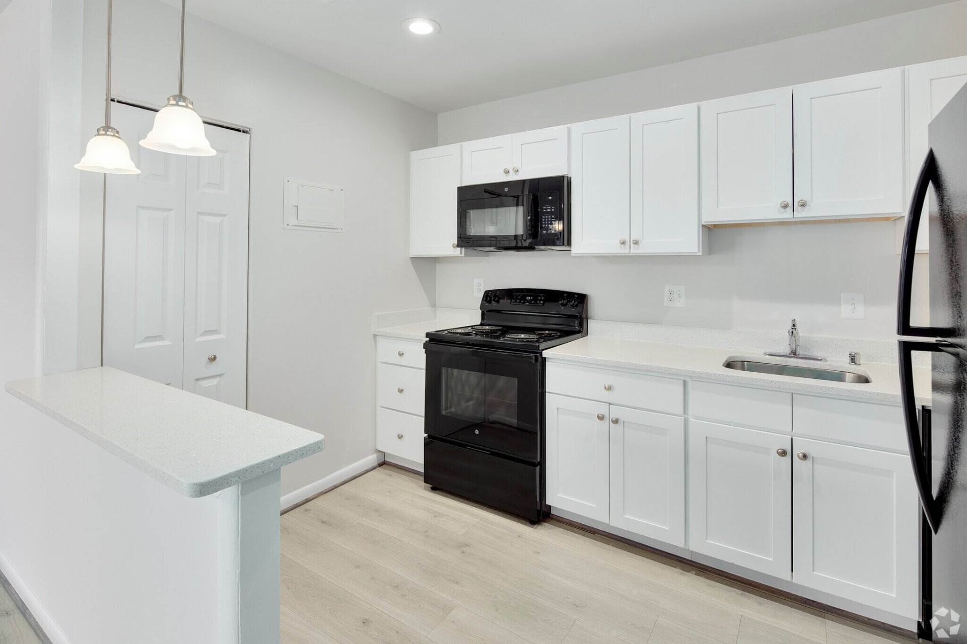 Two-bedroom white kitchen with black appliances and pendant lights